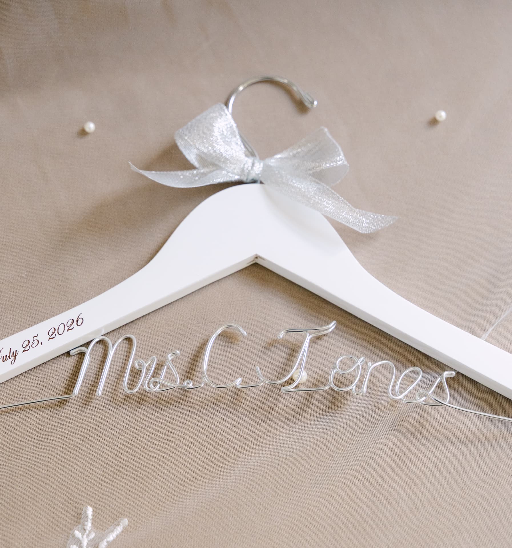 Custom white hanger with a wire name and wedding date on soft fabric