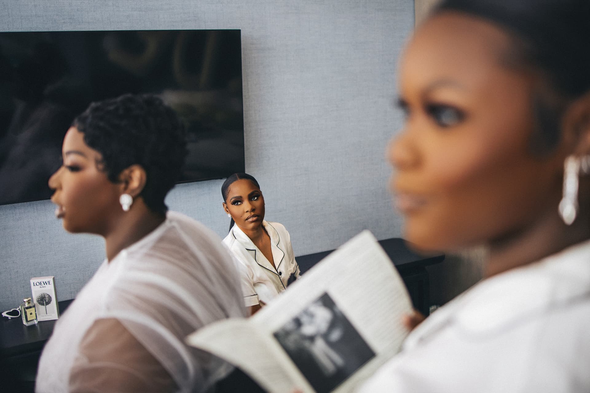 Bride and bridesmaids in a calm suite, one reading a magazine
