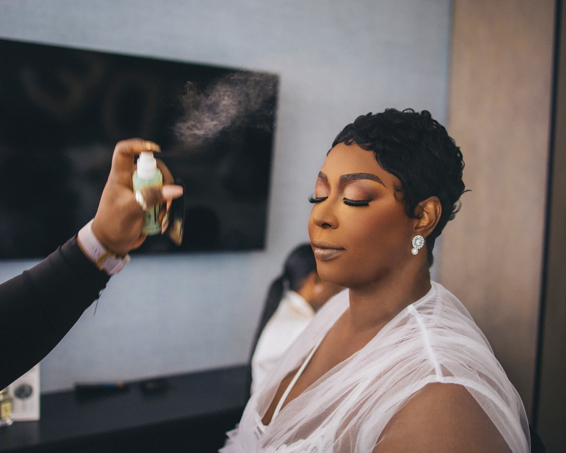 Makeup artist applying setting spray as the bride closes her eyes