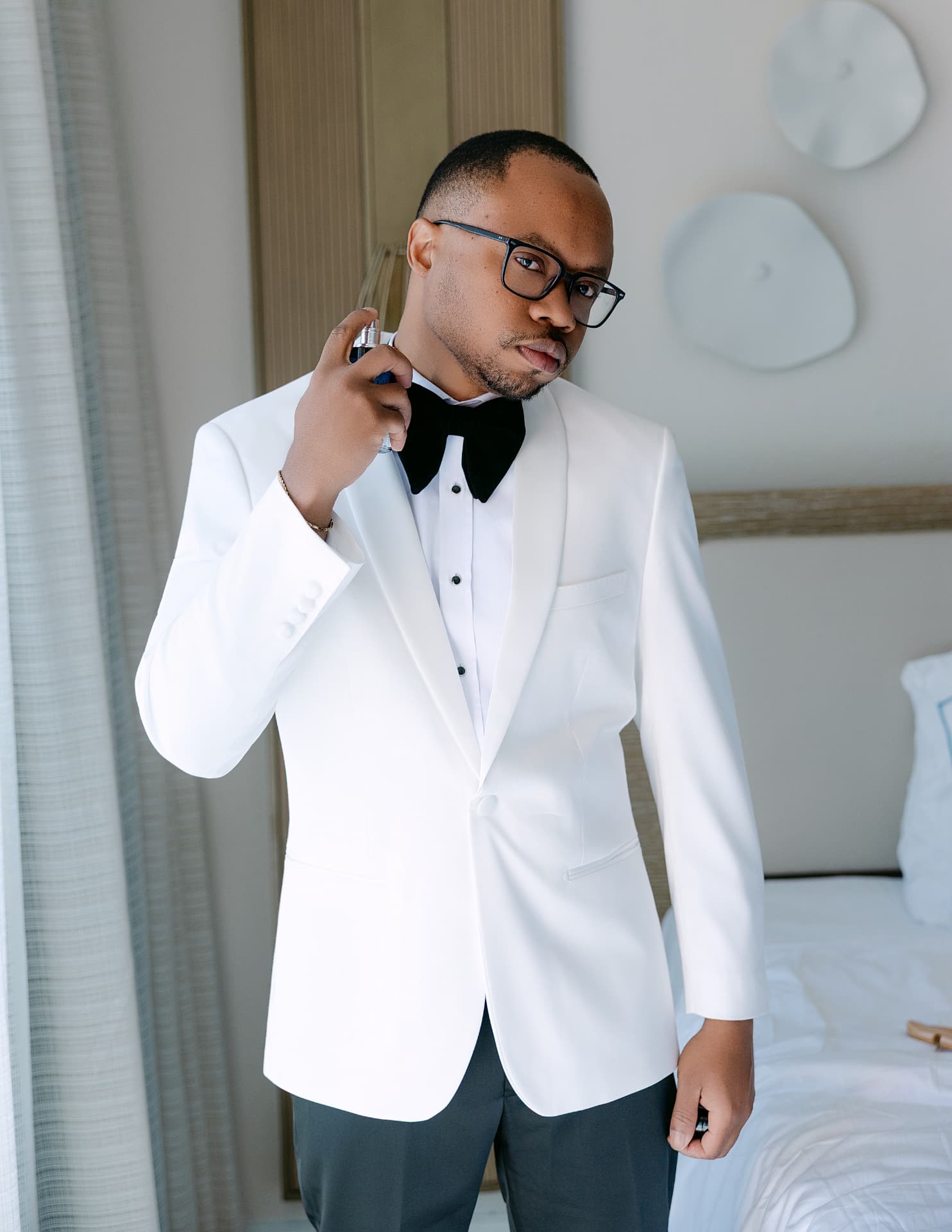 Groom in a white dinner jacket applying cologne