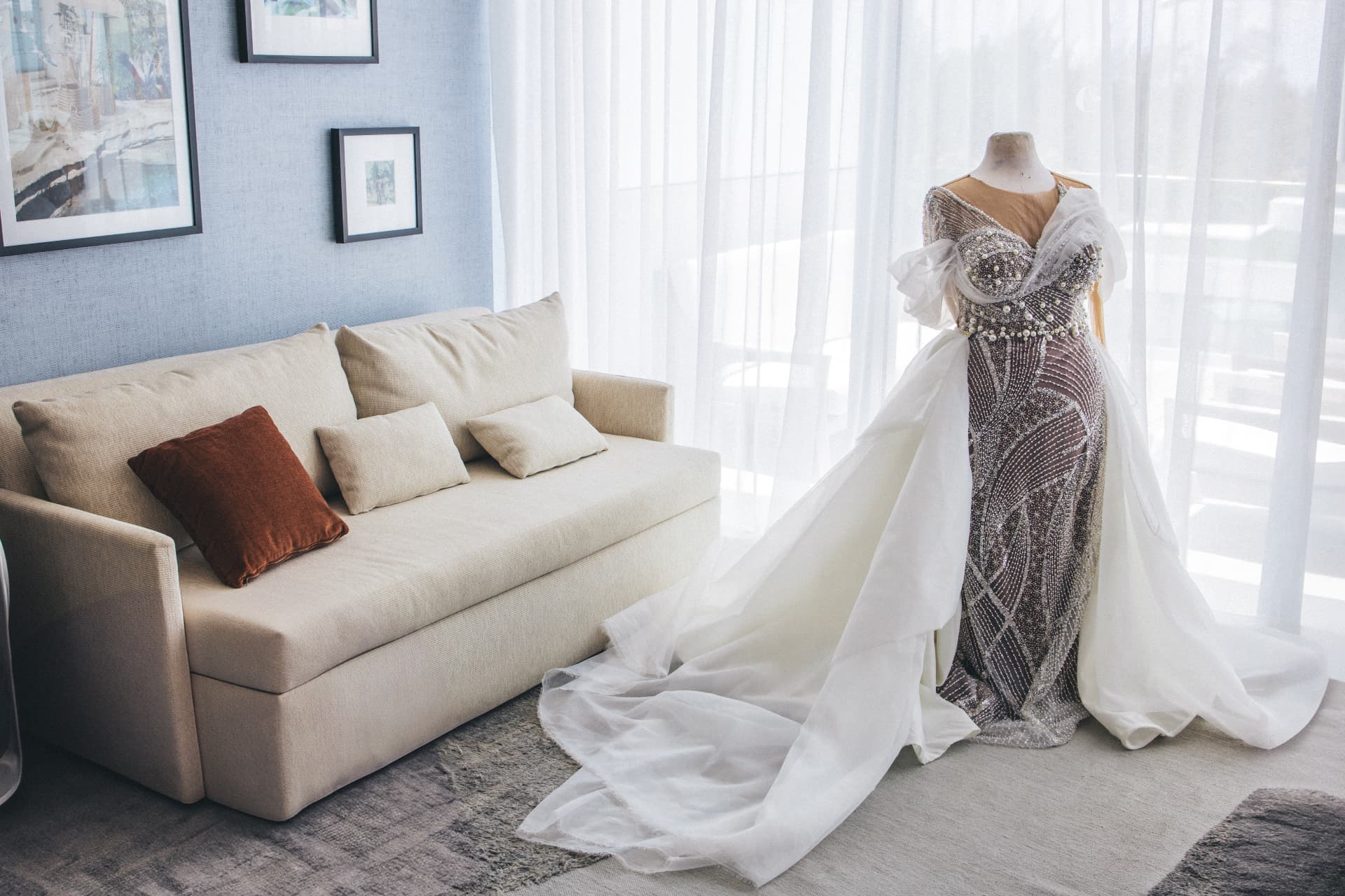 Beaded gown with a long organza train arranged beside a cream sofa