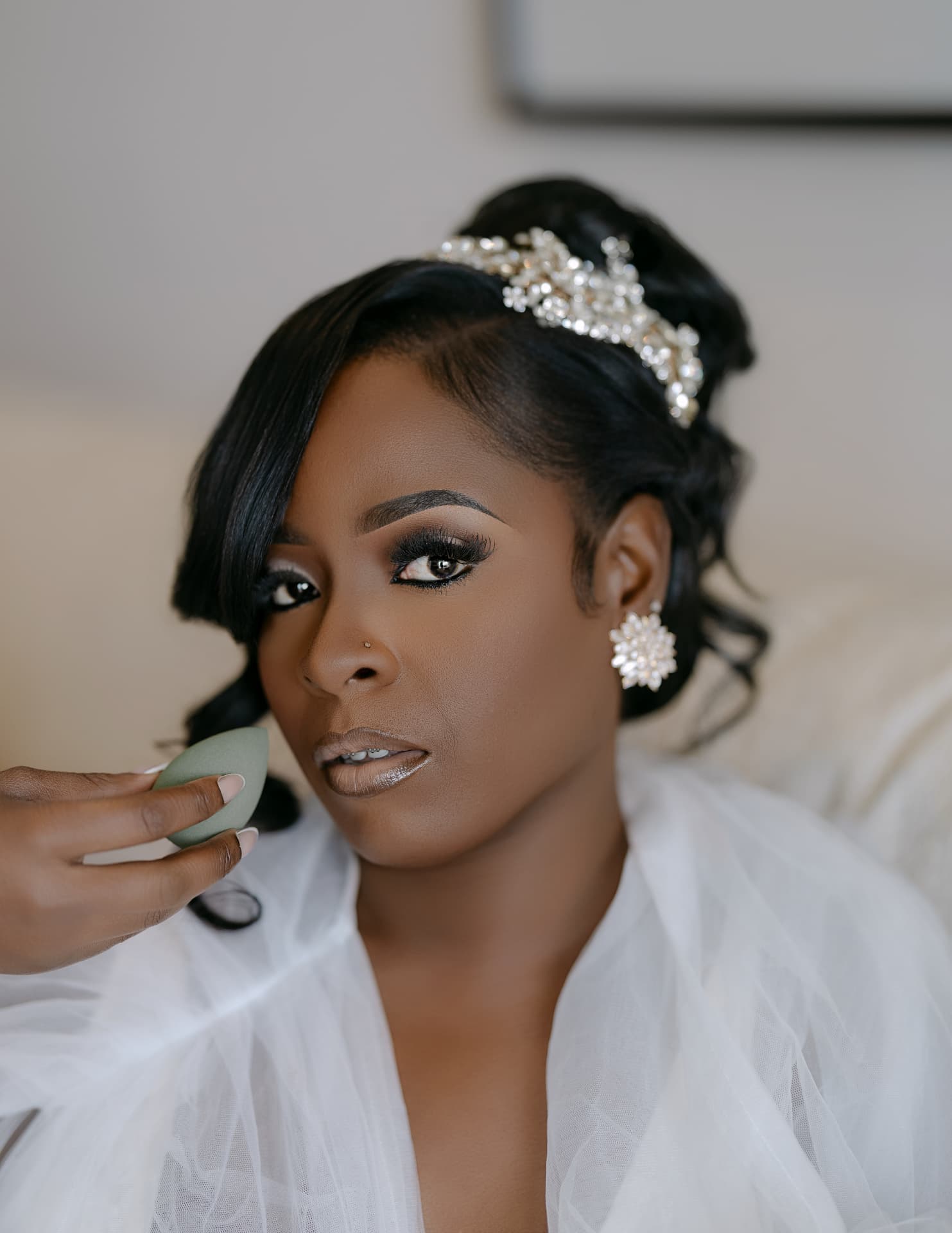 Bride having makeup finished, jeweled headpiece in place