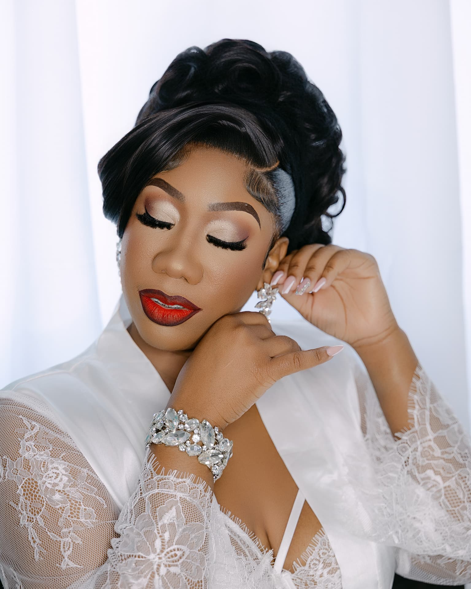 Bride resting her chin on her hand, eyes closed, in a lace robe